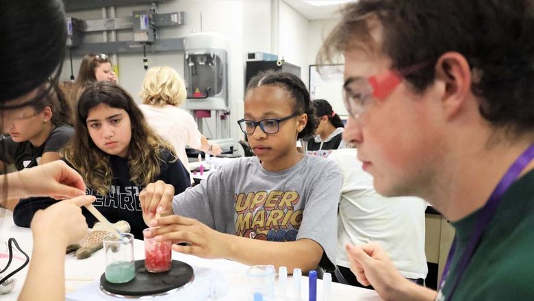 Several youth work with colored fluids in a lab at Penn State Behrend