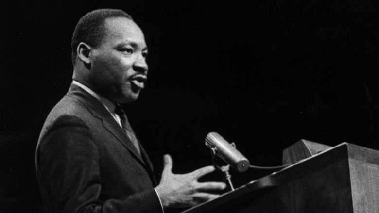 A black and white image of Martin Luther King speaking at a podium