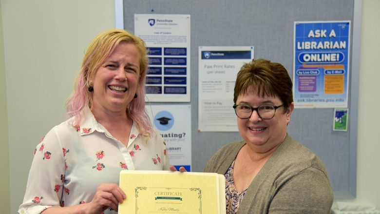 Lori Lysiak, reference and instruction librarian, presents Kelly Munly with the OAER Champion Award for her lightning talk at the campus's first Open and Affordable Showcase.