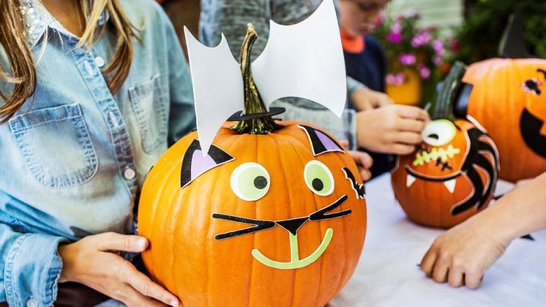 A decorated pumpkin held by a female