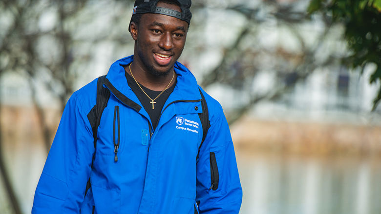 A male student walking next to the reflecting pond on Penn State Altoona's campus
