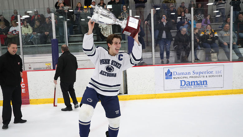 Team captain Christian Strang raises the College Hockey East trophy after the championship game against Robert Morris University in February. 