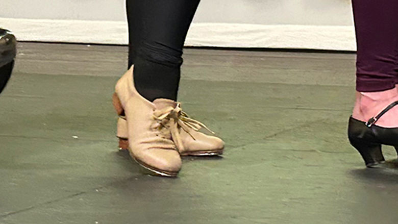 A close up on four sets of feet in different kinds of tap shoes