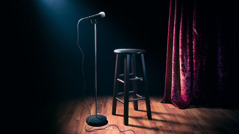 a photo of a stand-up comedy microphone and a stool on a stage