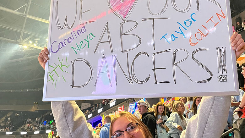Cami Santoriello (holding sign) and Adriana Quintal support Penn State Altoona’s dancers in the student section