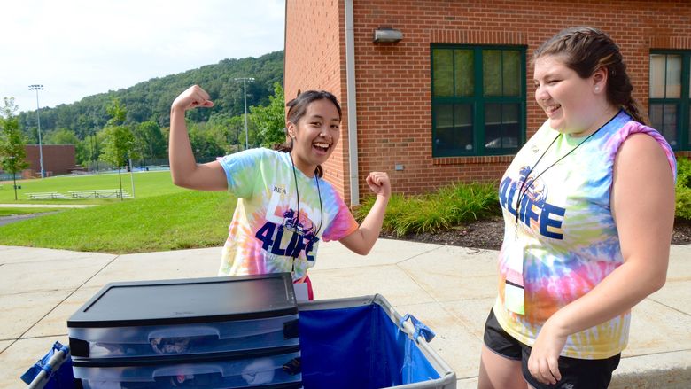 Two female students pose for a photo by a moving cart at Penn State Altoona.