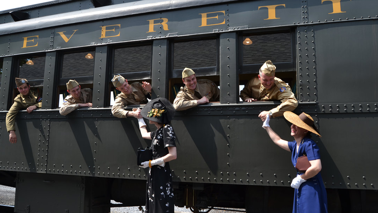 WWII reenactors pose near a train
