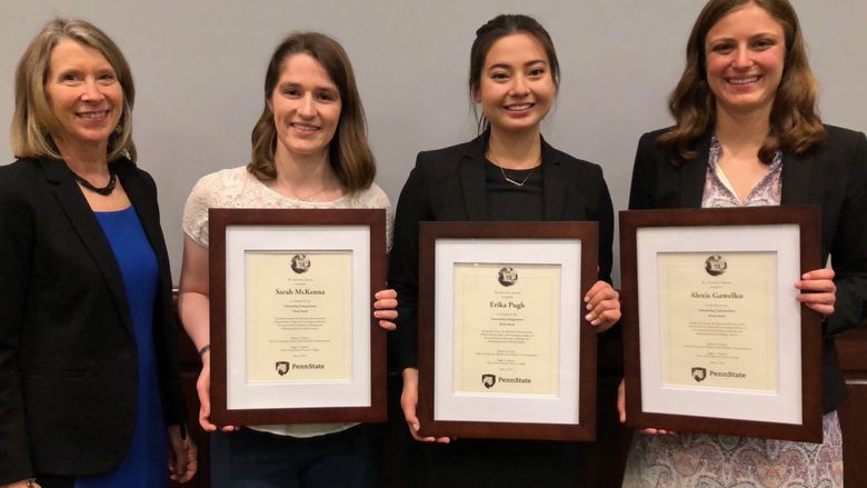 four females standing, three holding award plaques