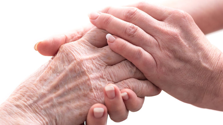 A pair of younger hands holding a pair of older hands