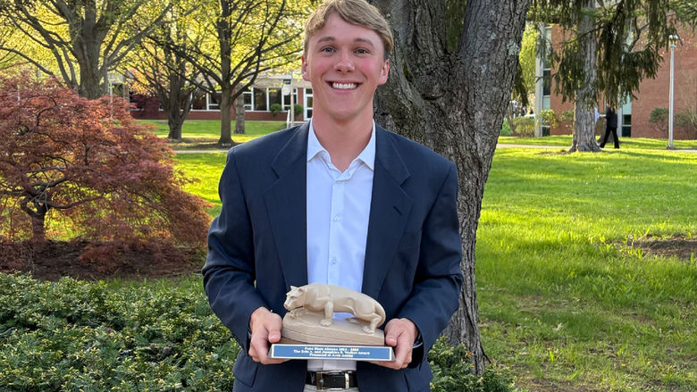 Student Arch Ackley poses with his Walker Award statue