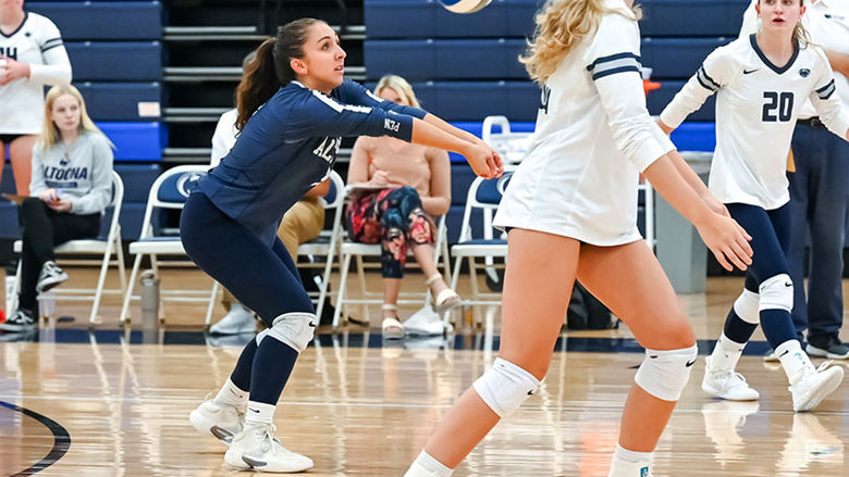Penn State Altoona volleyball player Anna Batrus prepares to dig during a volleyball game, surrounded by teammates on the court.