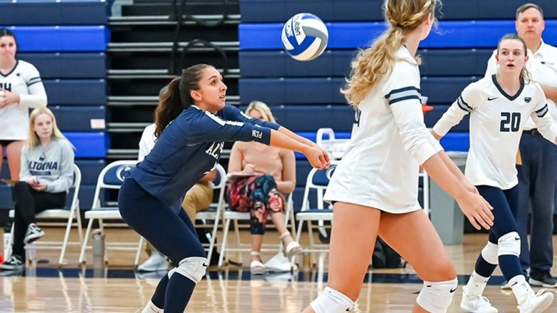 Penn State Altoona volleyball player Anna Batrus prepares to dig during a volleyball game, surrounded by teammates on the court.