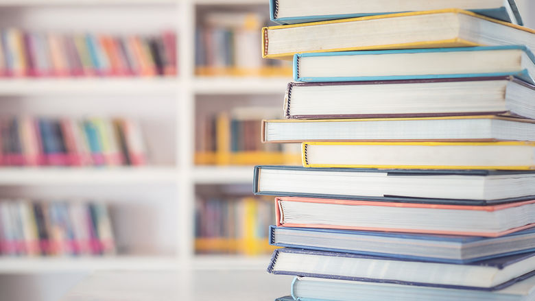 A pile of textbooks on a white table