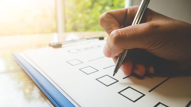 A hand holding a pen checking items off a list