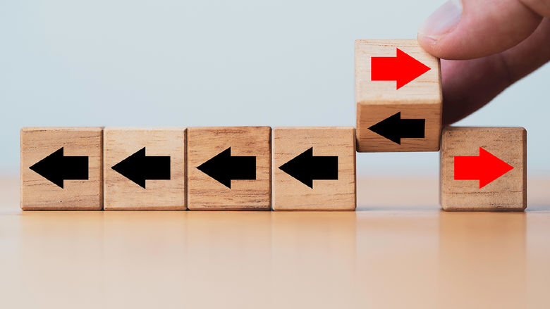 a series of small wooden blocks with arrows on them and a hand shifting the arrows from left to right