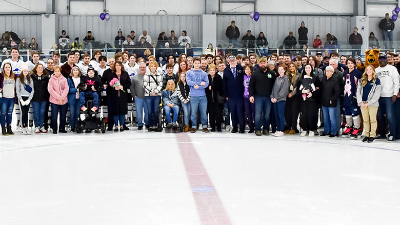 Players from both hockey teams, event organizers, and honorees pose for a group photo.