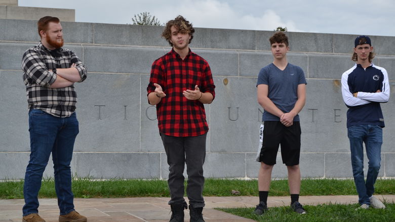 Four students standing in front of a wall