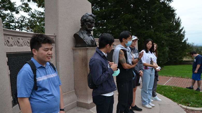 International and domestic students standing in front of a memorial