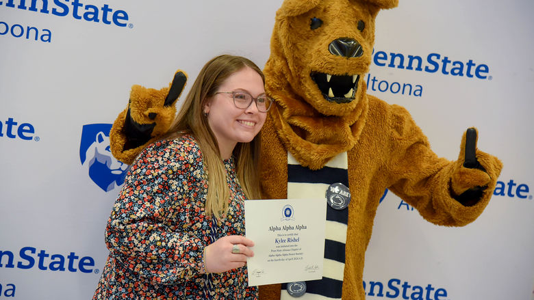 Psychology major Kylee Rishel poses with her certificate and the Nittany Lion after the induction ceremony. 
