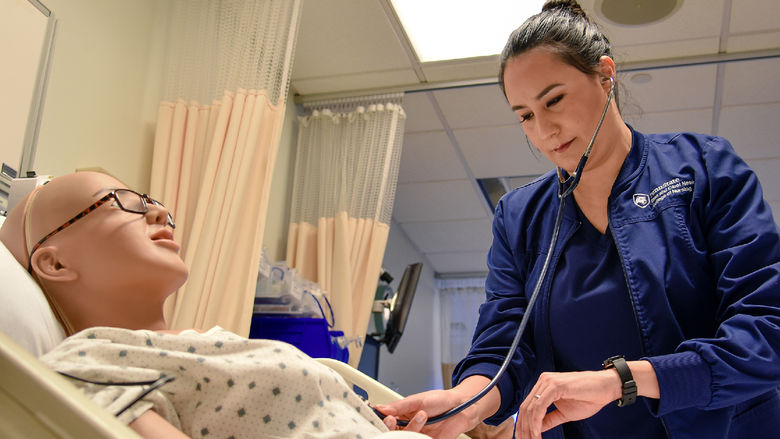 Paola Jaramillo Calderon interacts with a mannequin in Penn State Altoona's nursing simulation lab.
