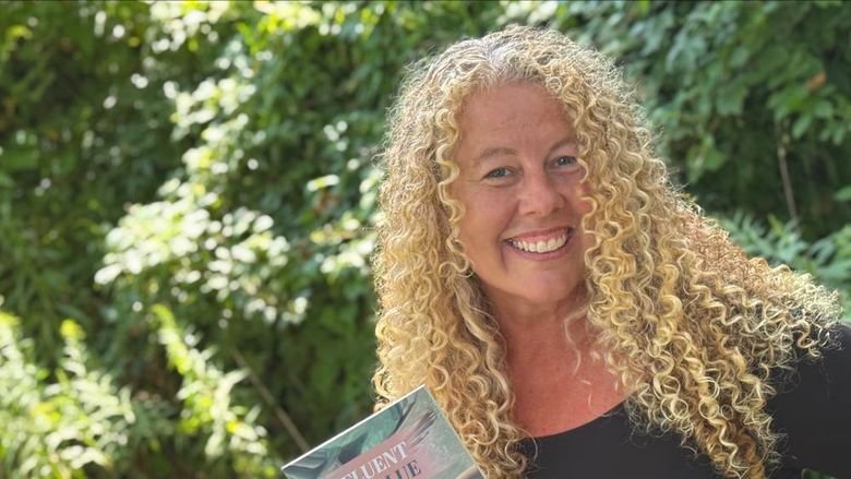 Penn State Altoona Professor Erin Murphy holding a copy of her latest book Fluent in Blue