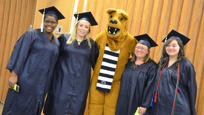 Graduates pose with the Nittany Lion at Fall 2017 Commencement ceremony.