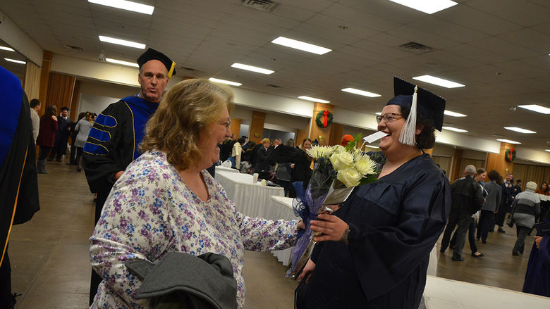 A proud family member presents flowers to a graduate at the Fall 2017 Commencement ceremony