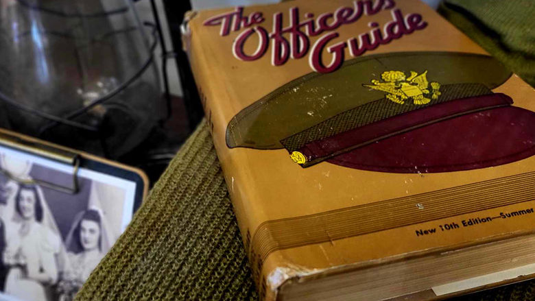 Personal items belonging to John C. Halloran now on display in the Smith Building, including a book titled The Officer's Guide and a wedding photo.