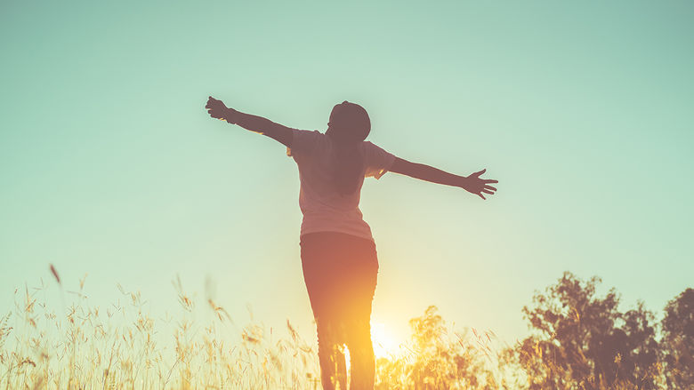 A woman standing in a field posing in the sunset