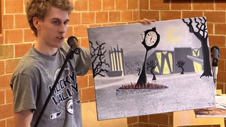 Student Talon McKendree displays an original painting of the Penn State Altoona campus in the style of German Expressionism.