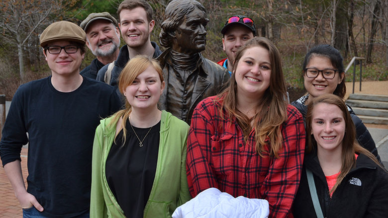 History students and faculty posing with a statue