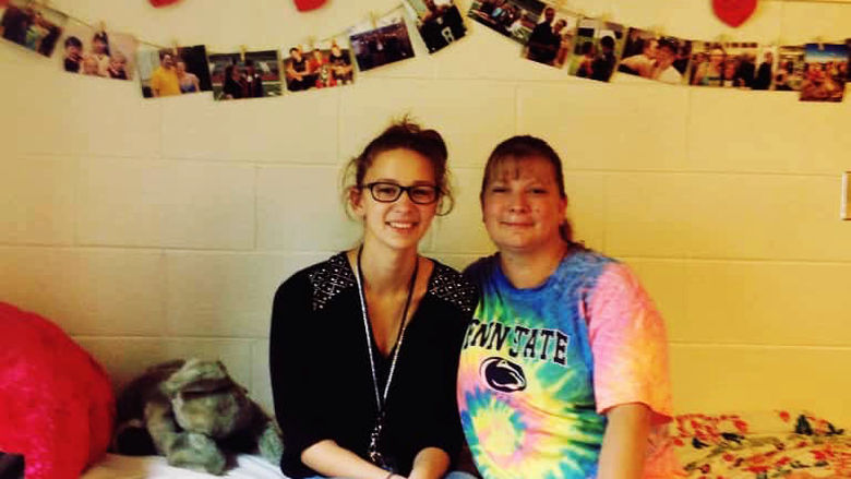 Gabrielle Davidson sits with her mother on the bed in her residence hall room.