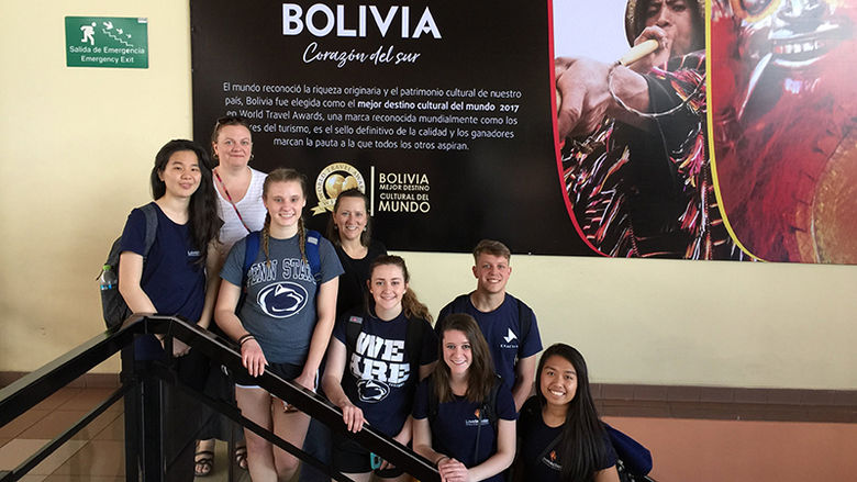 The team poses below this Bolivian poster while waiting at the airport.