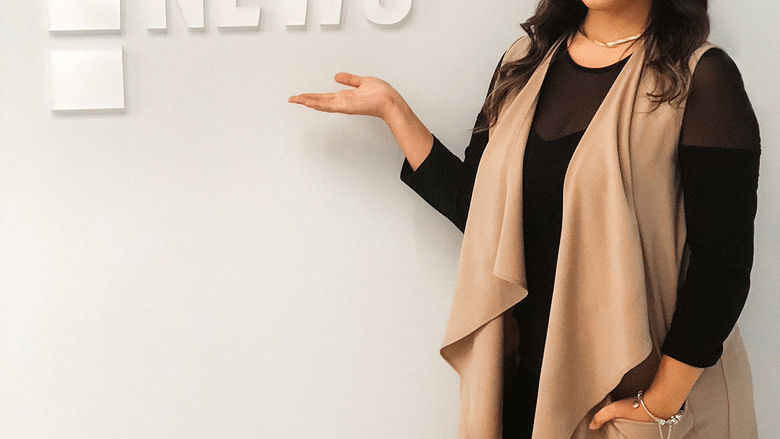 Catherine Rivera Chardon poses by the E! News logo during her internship