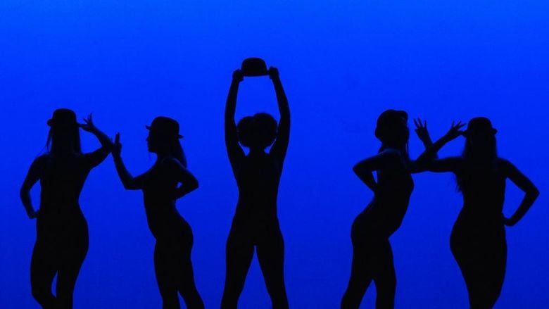 Penn State Altoona students do a jazz dance in front of a blue background