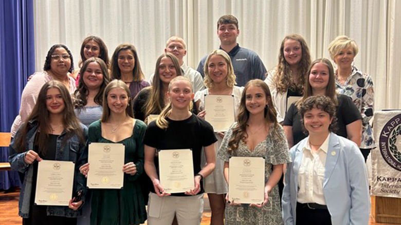 A group of education students and faculty pose for a photo at an education honor society induction ceremony