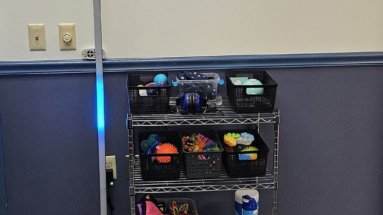 a tall, skinny light standing next to a small cart containing fidget spinners and sensory objects
