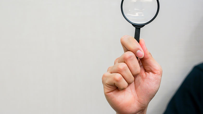 close up man hand holding magnifier glass for searching background concept