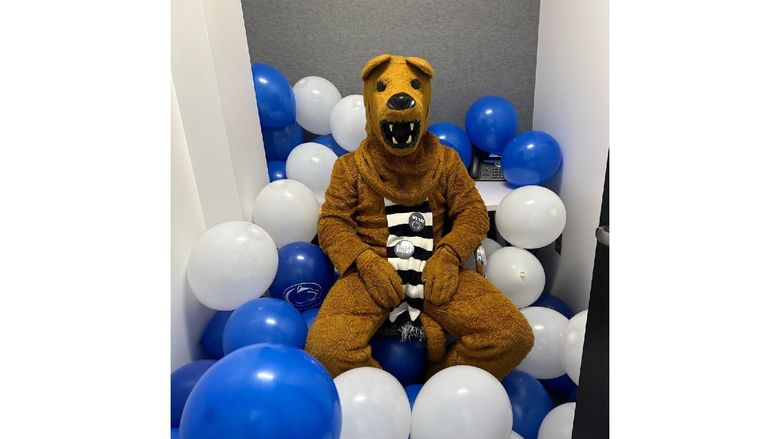 The Nittany Lion sits in the middle of a bunch of blue and white balloons