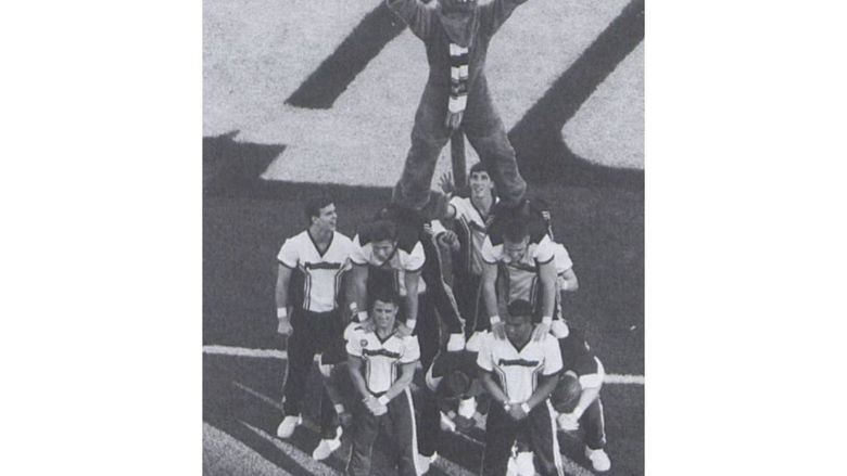 A group of male cheerleaders holds the Nittany Lion on the sideline of a football game in 1998