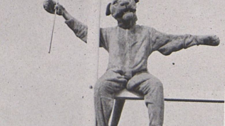 The Nittany Lion sits on top of a goal post, holding a baton, in 1940.
