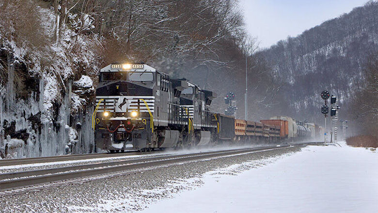 A photo of a locomotive on a track surrounded by snowy mountains