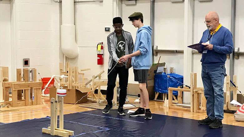 A pair of students compete in the 2023 PA Science Olympiad at Penn State Altoona while a judge observes