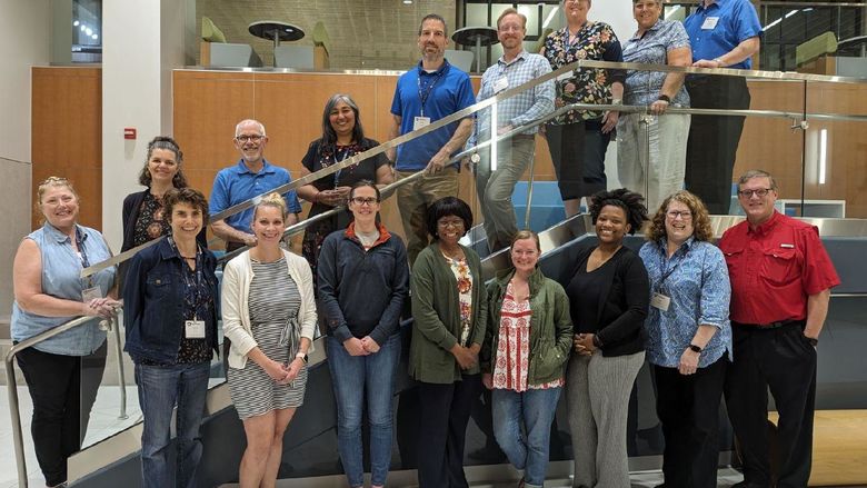 17 people pose for a group photo on and below a set of stairs