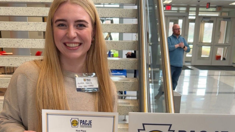 Madison Adamiak holding a certificate for first place in the PACJE Student Poster Competition