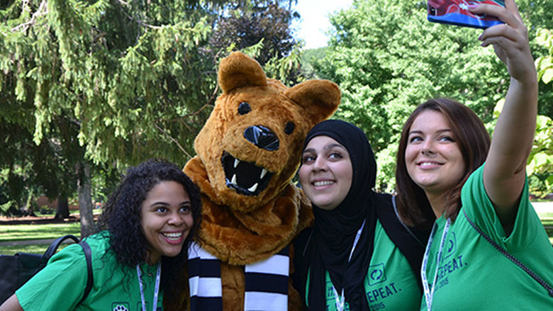 Three young ladies pose with the Nittany Lion