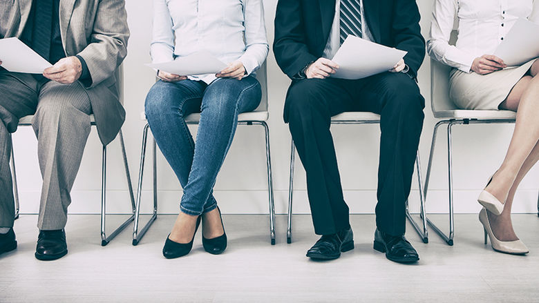 Photo of four men and women seated in a row and waiting for an interview