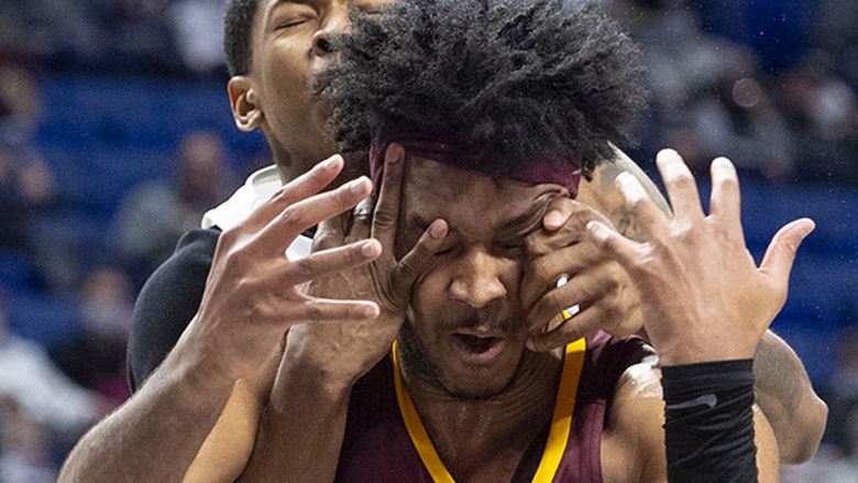 Basketball player wrapping hands around opponents head for a foul