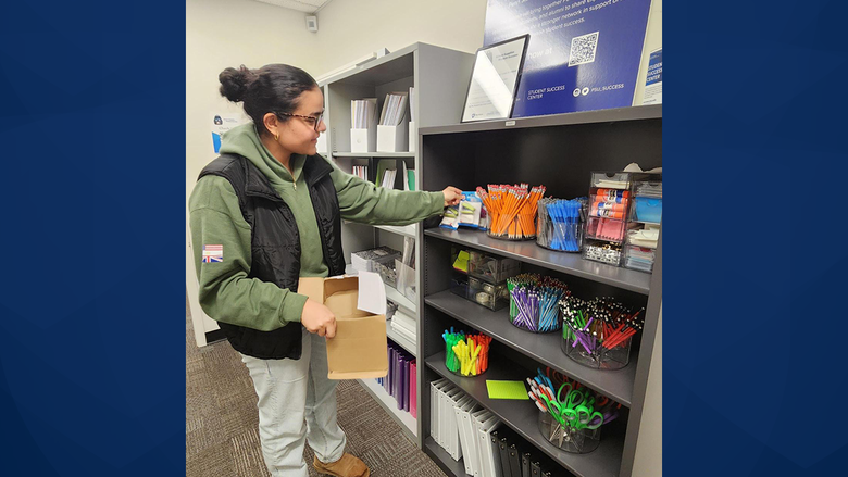 Student filling box with school supplies