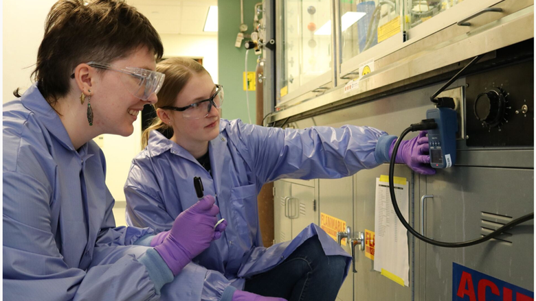 Two students in lab coats and goggles